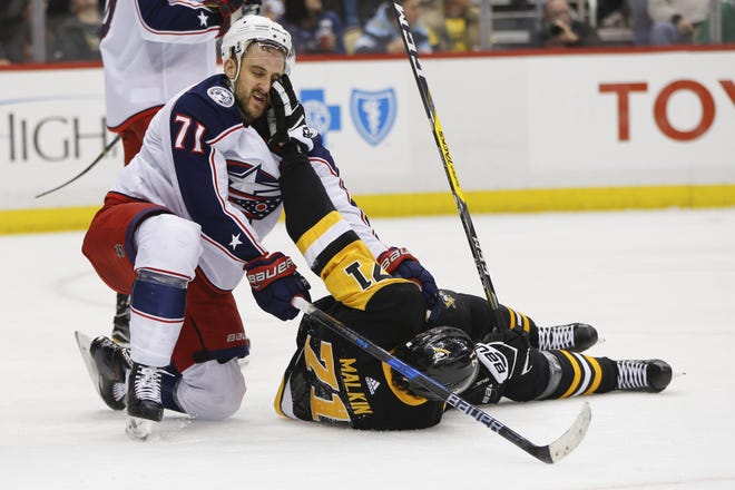 The Penguins' Evgeni Malkin pokes at the Blue Jackets' Nick Foligno after being knocked down during the second period. [Keith Srakocic/The Associated Press]