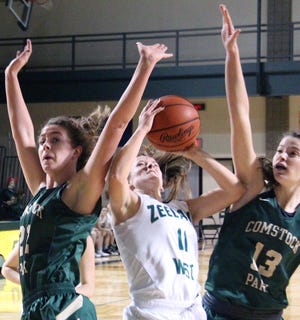 Zeeland West's Lucy Bouvier splits a pair of Comstock Park defenders on her way to the basket on Friday at Zeeland West. [Dan D'Addona/Sentinel staff]