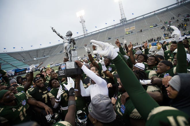 South Florida head coach Charlie Strong lifts up the Birmingham Bowl trophy after the Birmingham Bowl NCAA college football game, Saturday in Birmingham, Ala. South Florida defeated Texas Tech 37-34. [ALBERT CESARE / ASSOCIATED PRESS]