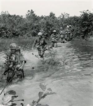 Members of the 27th Infantry Wolfhounds, part of the U.S. 25th Infantry Division, cross a muddy stream in Viet Cong country in 1967. | Associated Press file photo