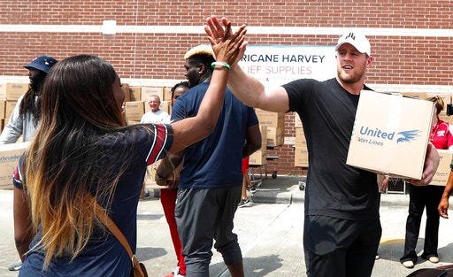 FILE - In this Sunday, Sept. 3, 2017, file photo, Anna Ucheomumu, left, high fives Houston Texans defensive end J.J. Watt after loading a car with relief supplies to people impacted by Hurricane Harvey in Houston. Watt had a modest goal when he launched a fundraiser to benefit Harvey victims. The Texans' three-time Defensive Player of the Year said he hoped to raise $200,000 in a video he posted on Twitter after a preseason game on Aug. 26. It took less than two hours to reach that number. Donations poured in from all over the world with several professional athletes chipping in. (Brett Coomer/Houston Chronicle via AP, Pool, File)