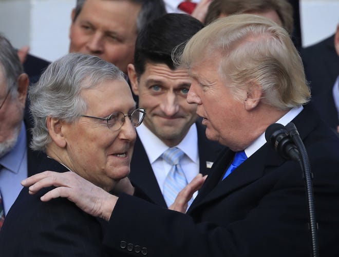 President Donald Trump congratulates Senate Majority Leader Mitch McConnell, while House Speaker Paul Ryan watches to acknowledge the final passage of tax overhaul legislation by Congress at the White House in Washington on Wednesday. [AP Photo/Manuel Balce Ceneta]