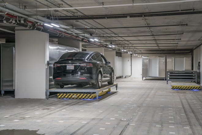 A car hitches a ride on a platform, which travels the space by reading squares on the floor that have different patterns of bar codes, in the garage at 520 West 28th Street in New York, Dec. 5, 2017. Digital amenities, controlled by voice commands and smartphone apps and use robots, are turning up across the New York area in condos, co-ops and rentals, even if users may have to contend with a few glitches. (Tony Cenicola/The New York Times)