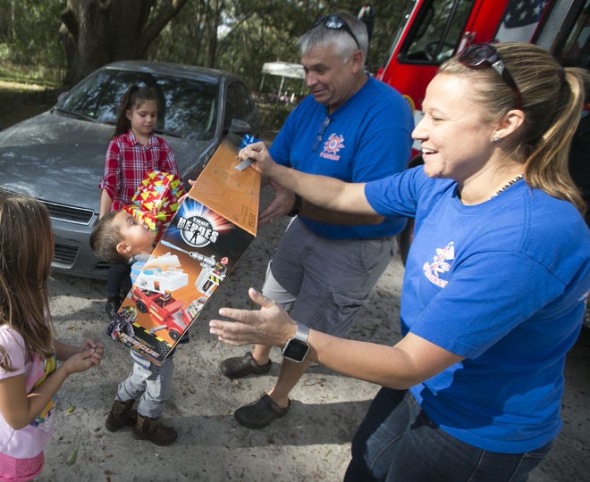 Lt. Jennifer Blakeney helps Roman Costa, 4, with a large fire truck at his home in Gainesville on Wednesday. Firefighters from Alachua County Fire Rescue delivered a firetruck full of gifts donated through efforts of Fire Rescue Professionals of Alachua County Local 3852 and donations from Ace Hardware and Home Depot to the Costas. The Costas lost nearly everything when their home burned down Oct. 27. [Alan Youngblood/Staff photographer]