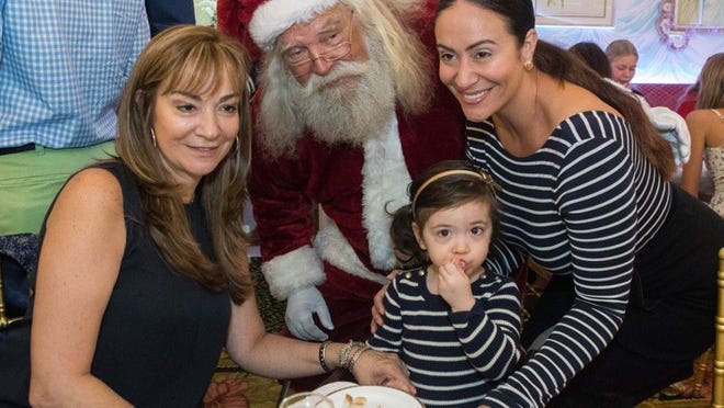 Martha Reyes, Isabella Hussey, 2, and Vanessa Reyes pose for a photo with Santa during the Santa Brunch benefiting Red Sneakers for Oakley at The Colony, Dec. 23, 2017. Damon Higgins/Daily News