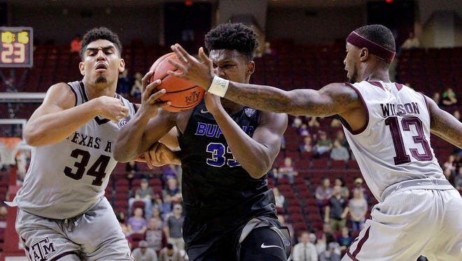 Buffalo forward Nick Perkins (33) drives through Texas A&M center Tyler Davis (34) and guard Duane Wilson (13) during the second half of a game Dec. 21 in College Station, Texas. (Associated Press)