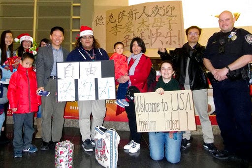 In this photo taken early morning of Dec 24, 2017 and released by China Aid, Li Aijie, center in red with her son Li Mutian poses for a photo with the airport staff and the staff and family members from China Aid near signs which reads "The people of Texas welcomes Li Aijie and son, Merry Christmas" and "Freedom Zhang Haitao" upon their arrival at the Midland International Airport in Midland, Texas. Li who is seeking political asylum in the U.S. is the wife of Zhang Haitao. Zhang who was sentenced to 19 years in prison had been a rare voice in China, a member of the Han ethnic majority and salesman by day who complained on social media about government policies he said were unfair to Muslim minority Uighurs. (China Aid via AP)