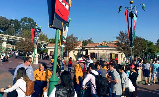 In this photo provided by Dan Greenspan, Disneyland park workers stop people from approaching the entrance as the turnstiles are roped off at the entrance of the park in Anaheim, Calif., Wednesday, Dec. 27, 2017. Power has been largely restored at Disneyland after an outage at the Southern California theme park forced some guests to be escorted off stopped rides. (Dan Greenspan via AP)
