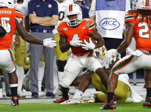 File-This Nov. 11, 2017, file photo shows Miami defensive back Jaquan Johnson (4) running after intercepting the football during the first half of an NCAA college football game against Notre Dame in Miami Gardens, Fla. Johnson thought about the NFL for a moment, but he's returning to Miami for his senior season. And the Hurricanes' standout safety says he's looking at Saturday's Orange Bowl against Wisconsin as a jump-start to 2018. (AP Photo/Lynne Sladky, File)