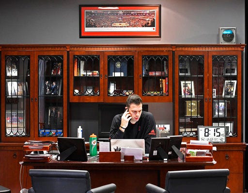 Louisville interim coach David Padgett talks on his cell phone as he starts the day in his office, Friday, Dec. 22, 2017, in Louisville, Ky. The office that formerly belonged to longtime coach Rick Pitino was locked and vacant until his firing in mid-October. Padgett slowly began moving in soon after. (AP Photo/Timothy D. Easley)