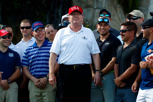 President Donald Trump smiles as he meets with members of the U.S. Coast Guard, who he invited to play golf, at Trump International Golf Club, Friday, Dec. 29, 2017, in West Palm Beach, Fla. (AP Photo/Evan Vucci)