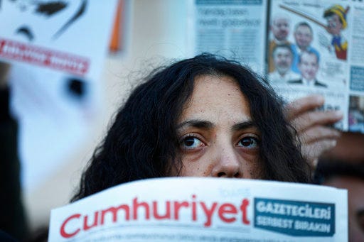 FILE- In this Tuesday, Oct. 31, 2017 file photo, demonstrators hold placards and copies of the Cumhuriyet daily newspaper as they stage a protest outside a court where the trial of about a dozen employees of the newspaper on charges of aiding terror groups, continues in Istanbul. In several countries news organizations are under attack in dramatic ways, as elected governments turn public outlets into their mouthpieces and try to silence critical voices. (AP Photo/Lefteris Pitarakis, File)