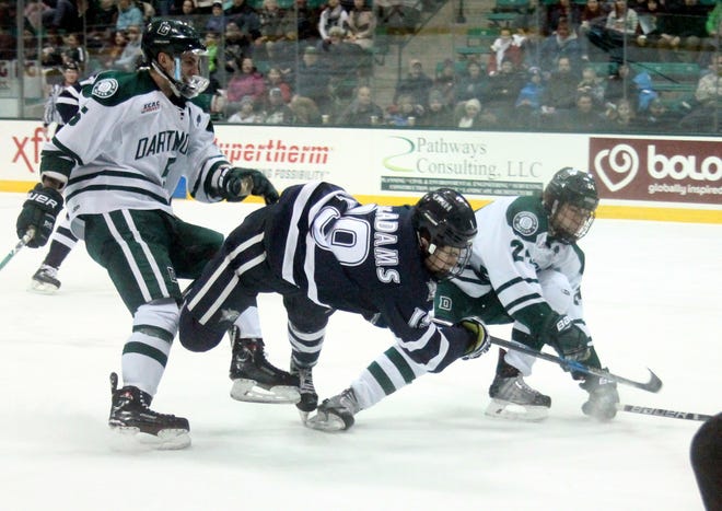 New Hampshire's Eric MacAdams, center, gets tripped up between Dartmouth's Tim Shoup, left, and Brendan Less during Friday night's game at Thompson Arena. Shoup was called for a penalty on the play. [John Doyle/Seacoastonline]