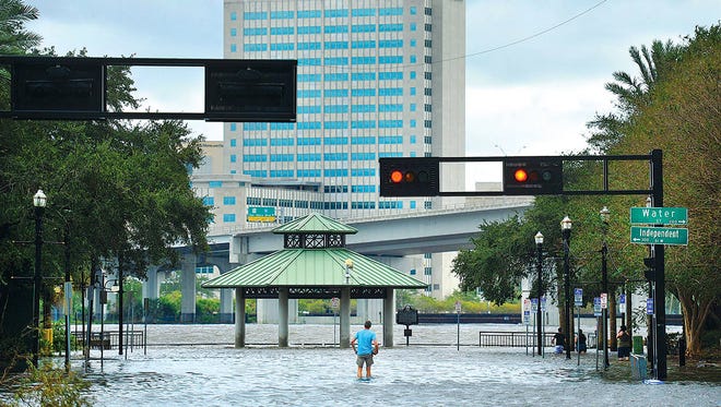 A spectator stands in the flooded intersection of Water Street and Independent Drive on Sept. 11 as Hurricane Irma floodwaters still covered many of downtown Jacksonville’s streets. The record high storm surge was causing unexpected flooding to low-lying areas. (Bob Self/Florida Times-Union)