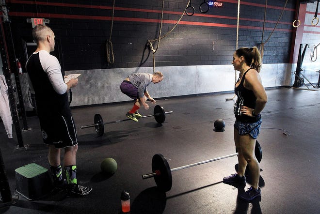 CrossFitter Jon Goodwin, left, works with Eric Wise and Shree Wise during their workout Wednesday. Gyms across the area should see more people over the next few weeks as resolutions for the new year are made. [JOHN CLARK/THE GASTON GAZETTE]