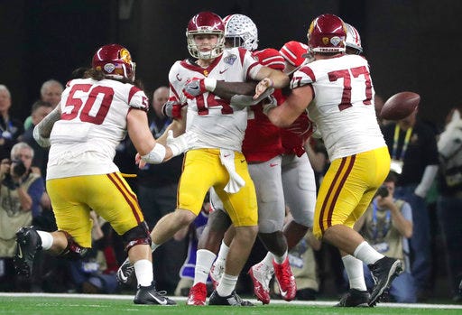 Ohio State defensive end Jalyn Holmes, center, hits Southern California quarterback Sam Darnold (14) ,forcing a fumble during the fourth quarter of the Cotton Bowl NCAA college football game in Arlington, Texas, Friday, Dec. 29, 2017. Also in the play are Southern California guards Toa Lobendahn (50) and Chris Brown (77). Ohio State, which recovered the fumble, won 24-7. (AP Photo/LM Otero)