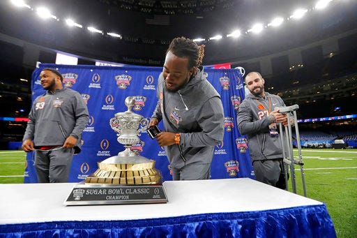 Clemson defensive tackle Jabril Robinson, center, defensive tackle Sterling Johnson, left, safety Alex Dalton get an up close look at the trophy during media day for the upcoming Sugar Bowl semi-final playoff game against Alabama, for the NCAA football national championship, in New Orleans, Saturday, Dec. 30, 2017. (AP Photo/Gerald Herbert)