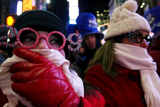 FILE- In this Dec. 31, 2008 file photo, Allison Smith of Jacksonville, Fla, left, tries to keep warm as she and others take part in the New Year's Eve festivities in New York's Times Square. Brutal weather has iced plans for scores of events in the Northeast U.S. from New Year’s Eve through New Year’s Day, but not in New York City, where people will start gathering in Times Square up to nine hours before the famous ball drop. (AP Photo/Tina Fineberg, File)
