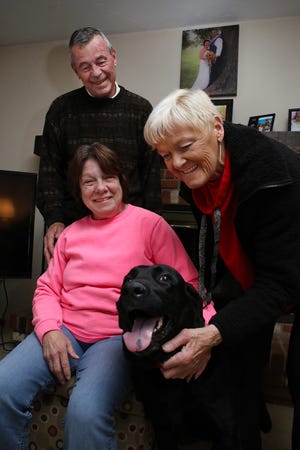 Ed Kovac, wife Kara Kovac (seated), roommate Chrissy Considine, and Considine's 6-year-old lab, Winston, pose for a photo in the Kovacs' house in Stow where they survived CO poisoning due to Winston waking Kara up.