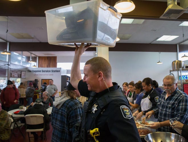 Eugene police officer David Clark hoists a container above his head as he moves through the crowded dining room at St. Vincent de PaulÃ¢Â?Â?s Eugene Service Station in Eugene, Ore. Friday, December 29, 2017. This is the fourth year the EPD has taken over the annual Christmas dinner, which is served to approximately 200 homeless men and women. The food is donated by BrunsÃ¢Â?Â? Apple Market and Eugene police officers and employees. (Brian Davies/The Register-Guard)