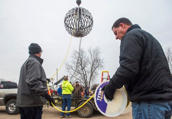 DAVID ZALAZNIK/JOURNAL STAR International Brotherhood of Electrical Workers Local 34 business manager Paul Flynn, left, and Matt Bartolo, secretary/treasurer for both Laborers Union Local 165 and of the West Central Building and Trades Council, unroll a tether Friday as the New Year's Eve lighted ball is lifted by crane in a test for the ball drop at the PNC Winterfest in downtown Peoria. The debut event, called the New Year's Eve Countdown, grew from a conversation six months ago between City Councilwoman Beth Jensen and Beau Sutherland, business development manager for the Peoria Civic Center.