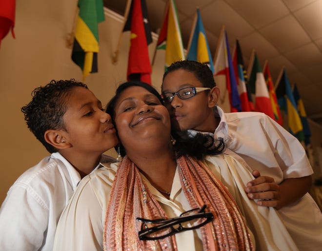 Samyra Figueroa, a single mother, gets hugs and kisses from her sons, Yeshua Rodriguez-Figueroa, 9, left, and Jeremy Rodriguez-Figueroa, 10, right, as they pose together in the Sanctuary of the Grace Fellowship Church on Southeast Maricamp Road in Silver Springs Shores. [Bruce Ackerman/Ocala Star-Banner] 2017