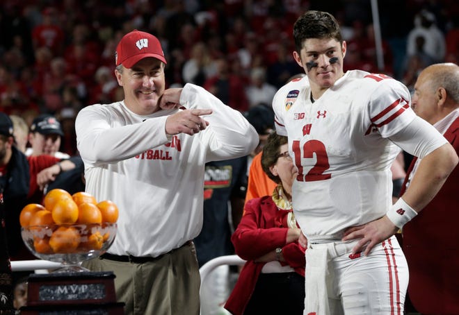 Wisconsin head coach Paul Chryst and quarterback Alex Hornibrook (12) stand next to the MVP trophy at the end of the Orange Bowl NCAA college football game against Miami, Saturday, Dec. 30, 2017, in Miami Gardens, Fla. Hornibrook won the MVP trophy. Wisconsin defeated Miami 34-24. (AP Photo/Lynne Sladky)