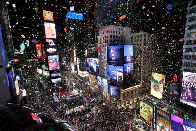 Confetti drops over the crowd as the clock strikes midnight during the New Year’s celebration in Times Square as seen from the Marriott Marquis in New York, Monday, Jan. 1, 2018. (AP Photo/Seth Wenig)