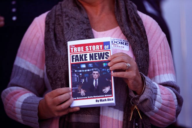 In a Nov. 17 file photo, a supporter holds up a "Fake News" book while Kayla Moore, wife of U.S. Senate candidate Roy Moore, speaks at a press conference in Montgomery, Ala. Would a story that seeks to unpack or drill down on a list of tiresome words and phrases be impactful or a nothingburger? Worse, would it just be tons of fake news? Well, dish all you want, but Northern Michigan's Lake Superior State University on Sunday released its 43rd annual List of Words Banished from the Queen's English for Misuse, Overuse and General Uselessness. [AP Photo/Brynn Anderson_File]