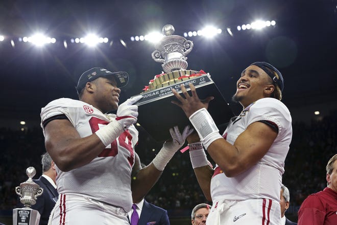 Alabama quarterback Jalen Hurts, right, and defensive lineman Da'Ron Payne (94) hold up the bowl trophy after defeating Clemson in the Sugar Bowl. [RUSTY COSTANZA/THE ASSOCIATED PRESS]