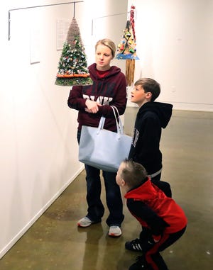 Stephanie Campbell and her sons, Lukas, 9, and Kolton White, 4, look at one of the pieces on display in the Barbara Cade Bonfire exhibit Tuesday, Jan. 2, 2018, at the Fort Smith Regional Art Museum. Lukas, a fourth-grade student at Woods Elementary School will have his photograph of the commisary building at the Fort Smith National Historic Site on display Jan. 5 through March 30 during the My Future Fort Smith exhibit. Opening in conjunction with Fort Smith's 2018 bicentennial, the exhibit includes works by students throughout the region and is comprised of works of art of all media depicting each young artists' ideal vision of Fort Smith. [JAMIE MITCHELL/TIMES RECORD]