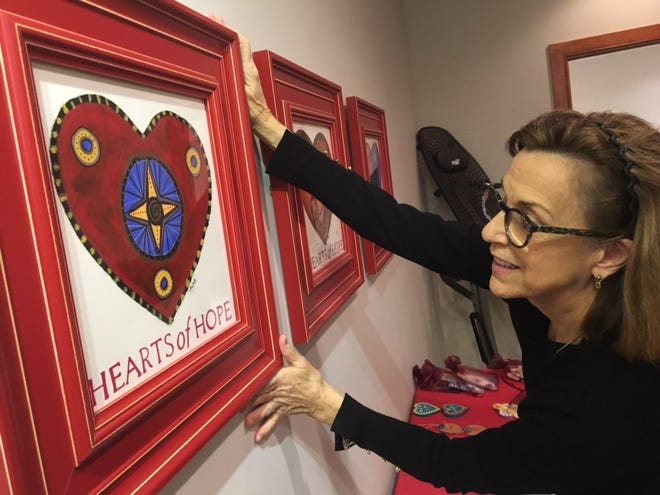 Judy Pedersen, of Perkasie, Pennsylvania, hangs artwork that is for greiving families. She is founder of the nonprofit ”Hearts of Hope” that has circulated heart-themed artwork and messages of hope with more than 80,000 people around the globe grieving in the aftermath of tragedy. [Marion Callahan/ STAFF PHOTOJOURNALIST]