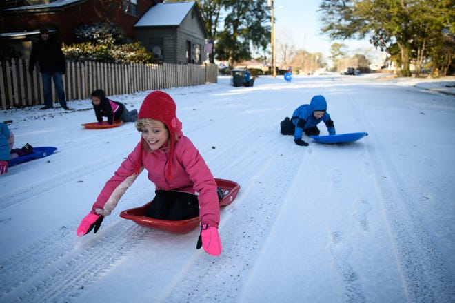 Children race their sleds down a snow covered Goodview Avenue on Thursday in Fayetteville. [Andrew Craft/The Fayetteville Observer]