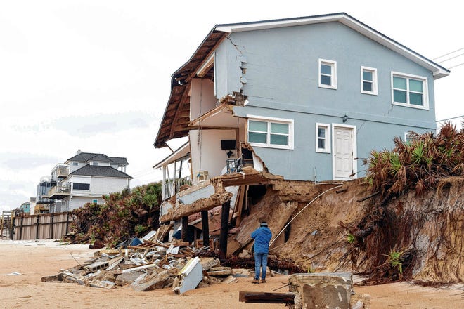 A beach walker watches as an unoccupied beachfront home collapses because of beach erosion in Ponte Vedra Beach. [PETER WILLOTT/ST. AUGUSTINE RECORD]