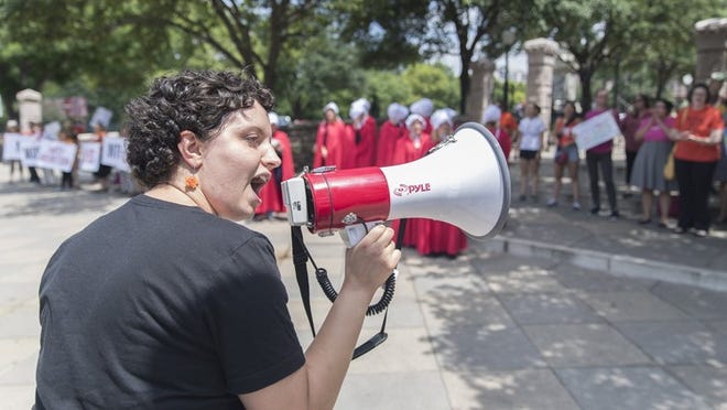 Hannah Thalenberg leads a chant with abortion rights activists dressed as characters from “The Handmaid’s Tale” in May to protest regulations contained in Senate Bill 8. RICARDO B. BRAZZIELL / AMERICAN-STATESMAN