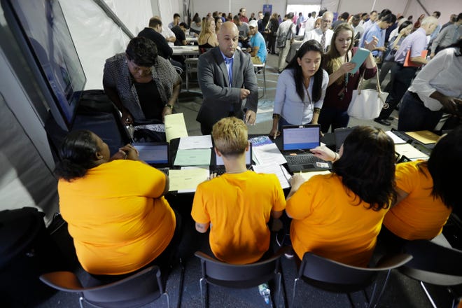 FILE - In this Wednesday, Aug. 2, 2017, file photo, job candidates are processed during a job fair at the Amazon fulfillment center in Robbinsville Township, N.J. On Friday, Jan. 5, 2018, the U.S. government issues the December jobs report. (AP Photo/Julio Cortez, File)