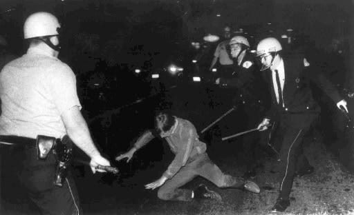 An Aug. 27, 1968, photo shows a demonstrator falling to the ground as he is pursued by police officers during the Democratic National Convention in Chicago. [AP Photo, File]