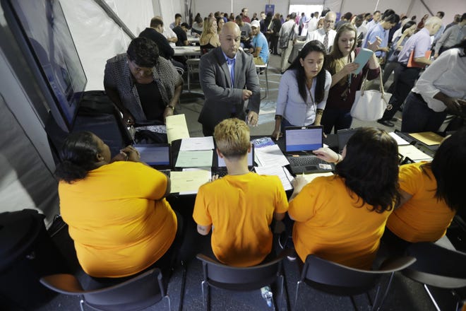 In this Aug. 2 photo, job candidates are processed during a job fair at the Amazon fulfillment center in Robbinsville Township, N.J. On Friday, the U.S. government issued the December jobs report. [AP Photo/Julio Cortez, File]