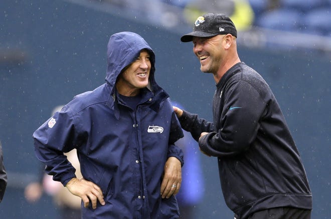 Seattle Seahawks head coach Pete Carroll, left, and Jacksonville Jaguars head coach Gus Bradley talk in the rain before a game on Sept. 22, 2013, in Seattle. The scheme that carried the Seahawks to consecutive Super Bowls (2013-14) has become increasingly popular around the league. [AP Photo / Ted S. Warren, File]