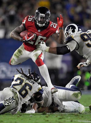 Atlanta Falcons running back Tevin Coleman (26) leaps Los Angeles Rams inside linebacker Mark Barron, bottom, and defensive end Aaron Donald during the second half of an NFL football wild-card playoff game Saturday, Jan. 6, 2018, in Los Angeles. (AP Photo/Mark J. Terrill)