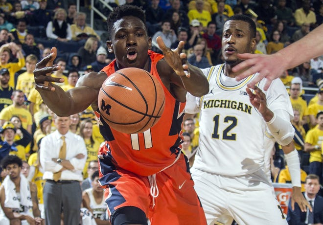 Illinois forward Greg Eboigbodin (11) reaches for a loose ball in front of Michigan guard Muhammad-Ali Abdur-Rahkman in the first half of Saturday's game. [Tony Ding/The Associated Press]