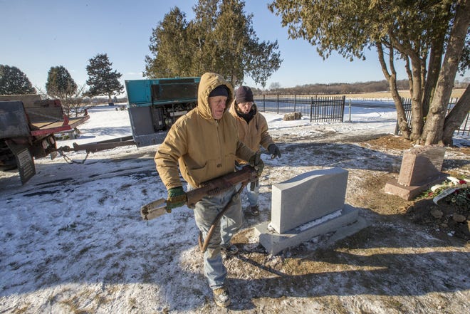 George Tillett, left, carries an air hammer for his daughter, Ginger Eterno, right, owner and president of Get Covered Inc. on Friday, Jan. 5, 2018, before a grave-digging demonstration at Scottish Argyle Cemetery in Caledonia. [ARTURO FERNANDEZ/RRSTAR.COM STAFF]