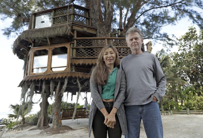 Lynn Tran and her husband, Richard Hazen, pose near their Australian pine treehouse Thursday in Holmes Beach. The couple is hoping the U.S. Supreme Court will hear their case after city and state officials ordered the treehouse removed. [CHRIS O'MEARA/AP]