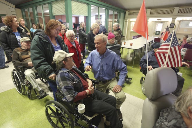 Gov. Bruce Rauner, kneeling at center, talks with members of the Illinois Veterans Home after a news conference Wednesday, Jan. 10, 2018, at Smith Hall on the campus of the Illinois Veterans Home in Quincy, Ill. Rauner has been staying at the facility since last week to better understand the operations of the home after it experienced a Legionnaires' disease outbreak. (Phil Carlson/The Quincy Herald-Whig via AP)