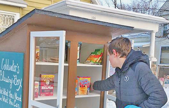 Jackson Beaty stocks the Blessing Box with food. The box is located at 106 Grand St., Coldwater.