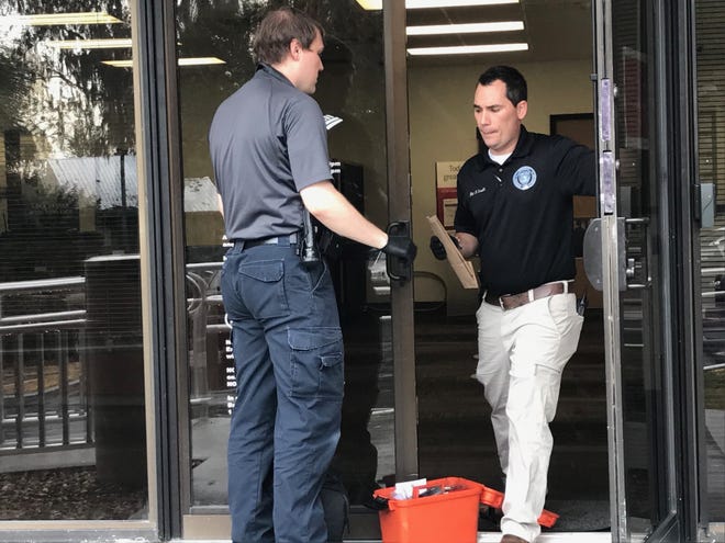 Ocala police evidence technician Andrew Rocafort and Detective Brandon Sirolli work the bank robbery scene Friday afternoon. [Austin L. Miller / Ocala Star-Banner]