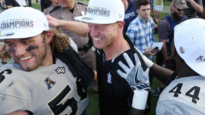 Coach Scott Frost celebrates with UCF players after they won the American Athletic Conference championship game against Memphis in December. The Knights followed that up with a victory over Auburn in the Peach Bowl to complete a 12-0 season. STEPHEN M. DOWELL/ORLANDO SENTINEL