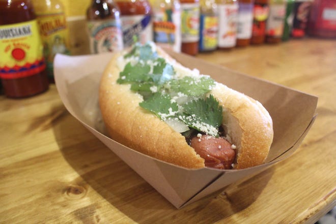 The Holy Molé features a ¼-pound black angus dog on an 8-inch hoagie bun topped with molé sauce, grilled onions, cotija cheese and cilantro. [PHOTOS BY JAN WADDY/THE NEWS HERALD]