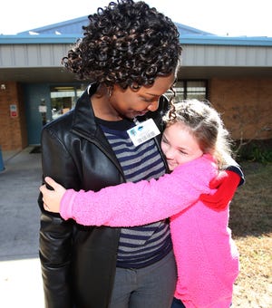 Amber Henderson, 7, a second grade student, hugs Assistant Principal Diana Elysee as she waits to get picked up in the car line at the end of the school day at Evergreen Elementary school in Ocala, Fla. on Thursday, Jan. 18, 2018. Four of five school board members have indicated that they would like to keep Evergreen Elementary open and have a private company come in and run the curriculum. The school board will vote Tuesday night to make the final decision about what will be done with Evergreen. [Bruce Ackerman/Ocala Star-Banner] 2018.