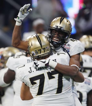 Central Florida wide receiver Tre'Quan Smith (4) embraces Central Florida offensive lineman Jake Brown (77) after the Peach Bowl NCAA college football game against Auburn, Monday, Jan. 1, 2018, in Atlanta. Central Florida won 34-27. (AP Photo/John Bazemore)